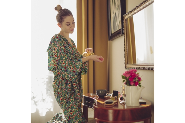 Woman applying perfume at vanity table in cozy bedroom morning routine