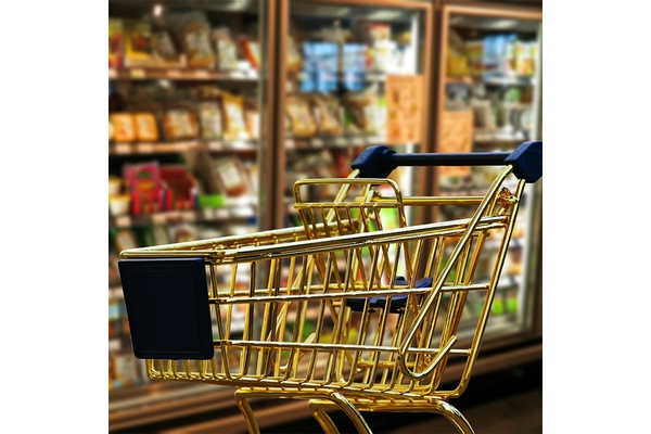 Golden shopping cart in supermarket aisle with blurred grocery shelves in background