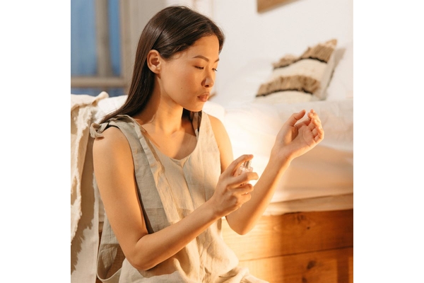 woman spraying perfume on wrist