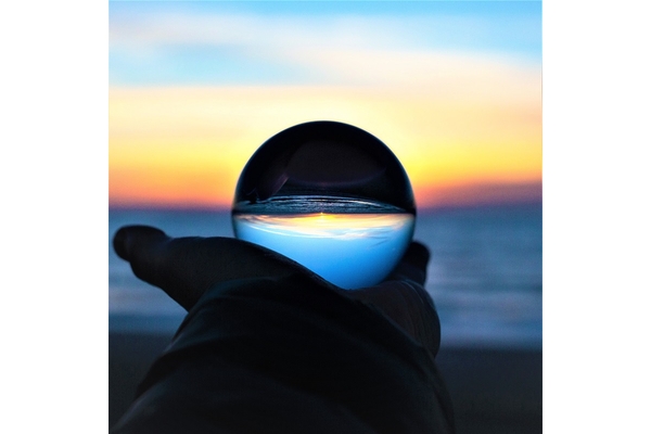 Image A person holds a crystal ball and looks at the sea.