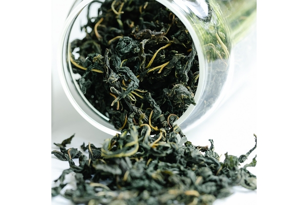 Green tea leaves spilling out of a jar.