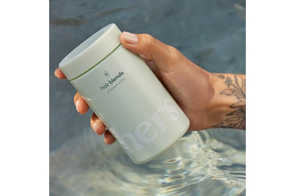 Image Product image of hand holding tin of supplements by a brand called Hair Blends.