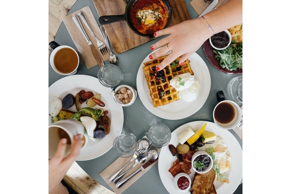 people grabbing food on the table and reaching for a waffle