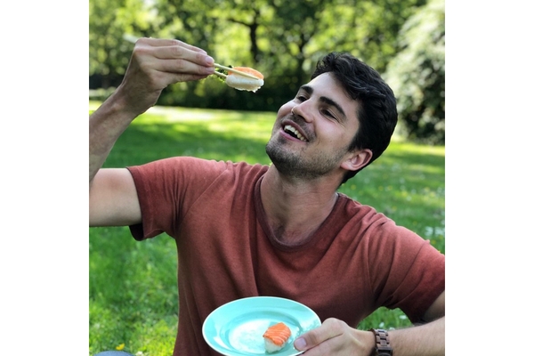 A man sitting in a garden and eating vegan fish filet.