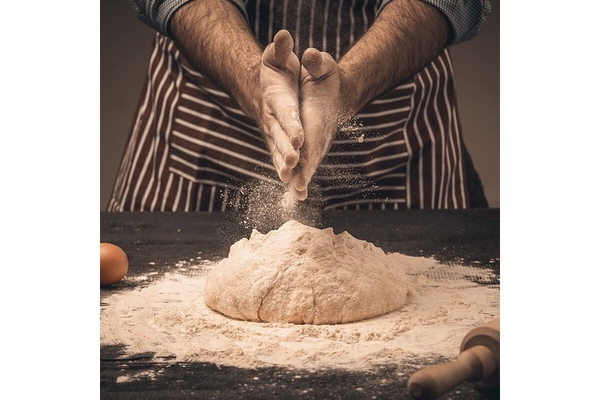 Image A man's hand dusting off flour on a table.