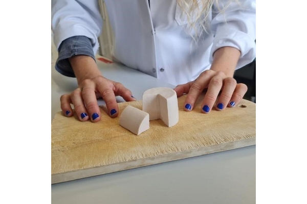 A piece of cheese has been cut out and placed on the table with a person wearing a laboratory coat.