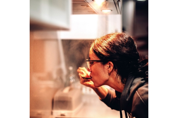 A lady is tasting something from a spoon.