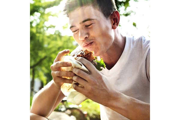 A man eating a plant-based burger and smiling.