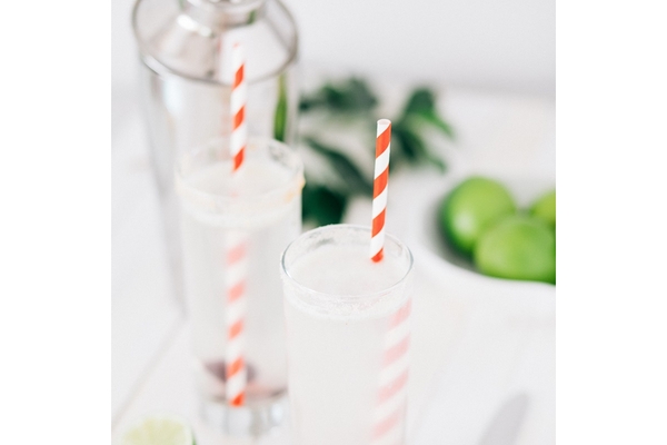 Two cups of soft drink are placed on a table with straws.