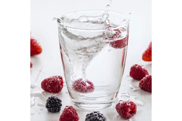 Berries are tossed in a cup of water.