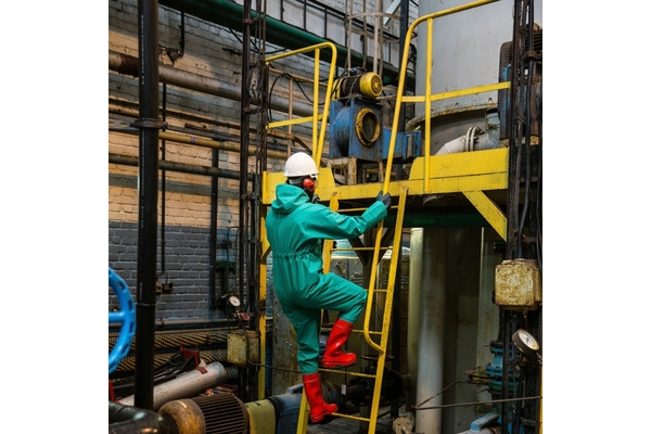 Image man in protective gear climbing down a ladder in a factory