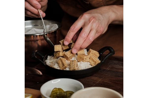 People add fried tofu to a bowl of rice.
