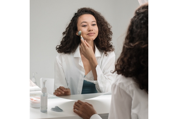 A woman applying her skin care looks at a mirror.