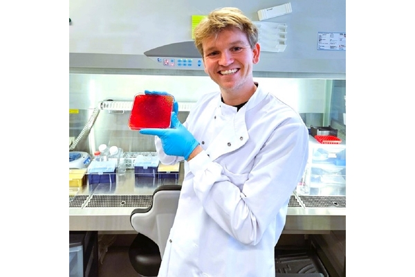 A scientist holding a sample of red food colorant in the lab.