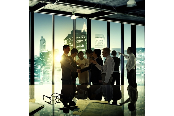 Image Several business people in a high room huge windows overlooking a city.
