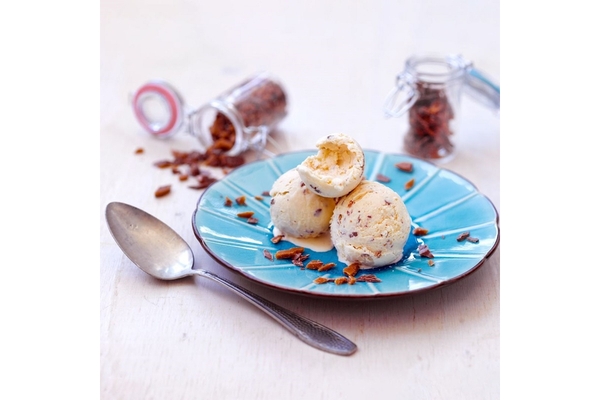 Ice cream balls are placed on a plate next to a spoon.