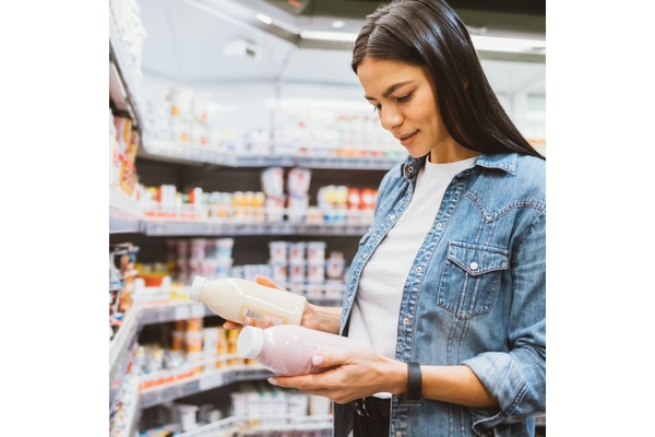 Image Woman choosing between two products in a supermarket.