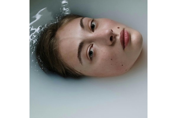Image A womans face peeping out of milky water.