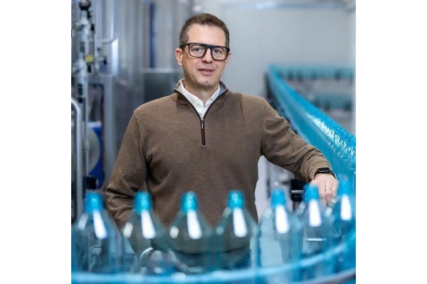 Image Man standing behind reusable PET water bottles.