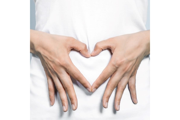 Two hands in a shape of a heart on the gut.