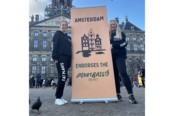 Lisette Weustenenk and Lea Goodett holding up a sign that says Amsterday endorses the plant based treaty.