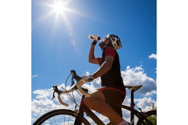 Athlete on a sports bicycle, drinking water from a bottle.