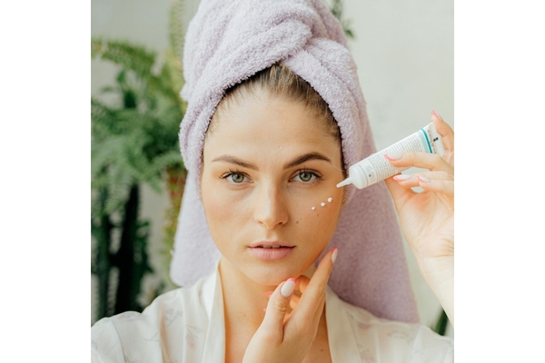A woman with dots of eyecream on her face.