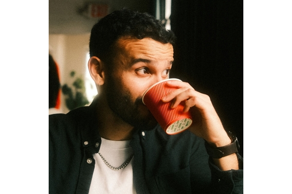 Image man sipping from a red coffee cup looking out of the window