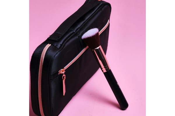 A makeup brush resting on a makeup bag.