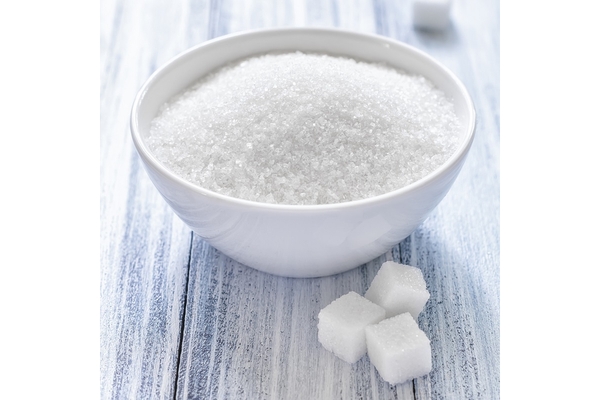 Sugar cubes are placed next to a bowl of sugar.