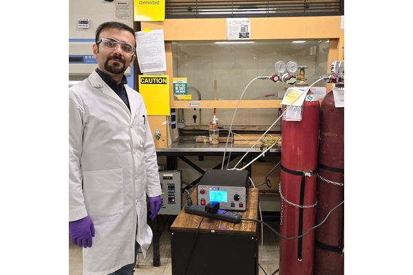 A male scientist standing in the lab in a white coat.