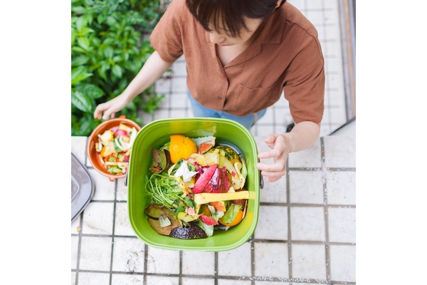 Top view of a woman throwing food waste in the dustbin.