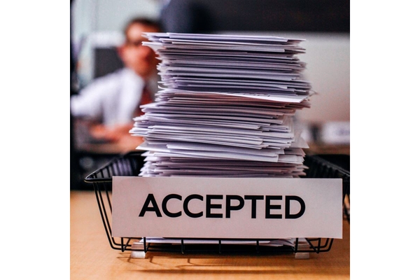 Image Stack of paper files in a basket marked Accepted.