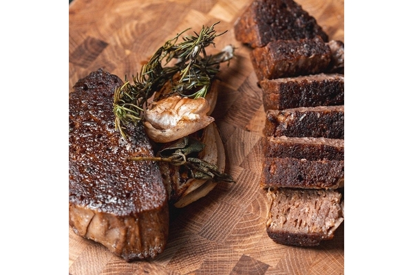 Image Two pieces of plant-based steaks on a wooden table.