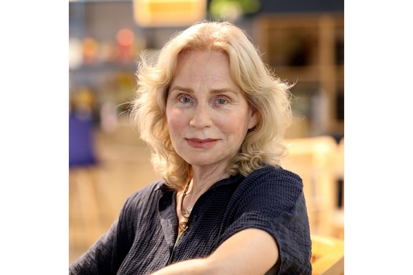 An smiling Israeli woman with golden hair in a blue top.