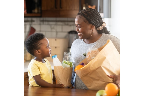 Mother and child putting away groceries in their kitchen.