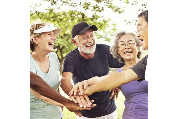 Group of seniors putting their hands together after exercising.