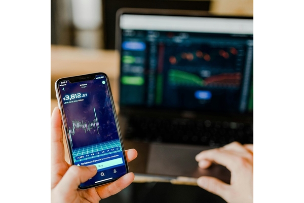 Image A hand holding a phone with the stock market on it.