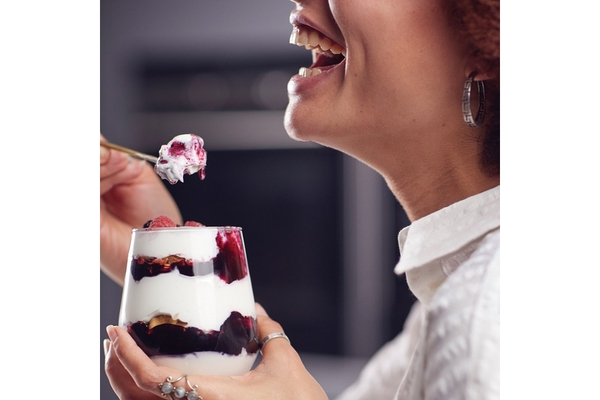 Image a woman eating yogurt.
