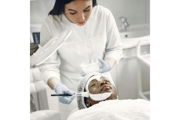 Image A dermatologist putting a face mask on her client.