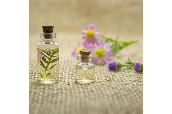 A small bottle of perfume with little flowers around it.