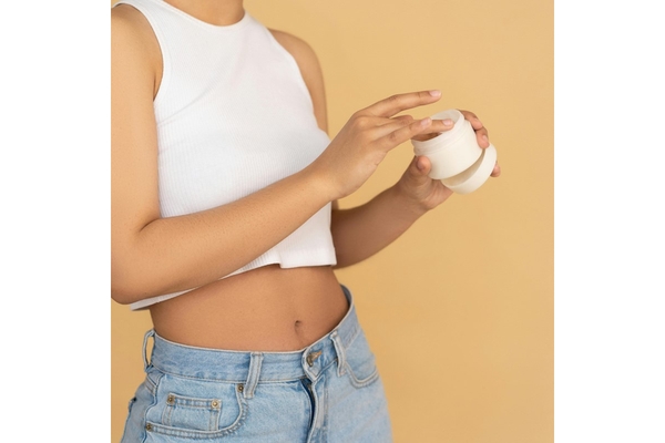 Image A woman putting her hand in a jar of skin cream.