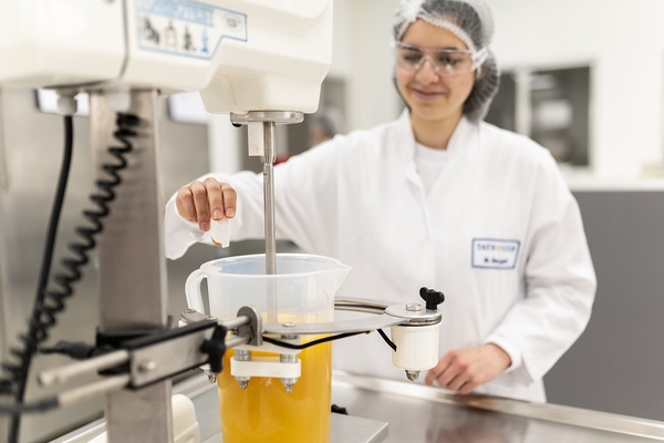 a food scientist mixing a yellow beverage in the lab.