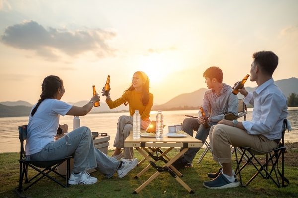 Image two young men and two young women drinking beer on the beach.