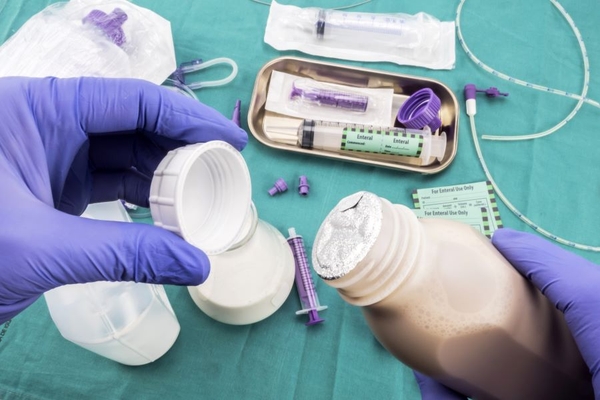 Holding medical bottle and closure in hands wearing gloves.
