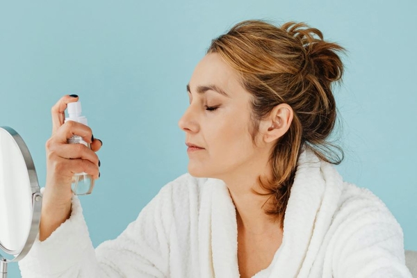 Image A woman using a spray on her face.
