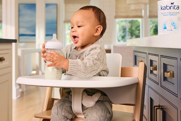 an infant holding a bottle of milk.