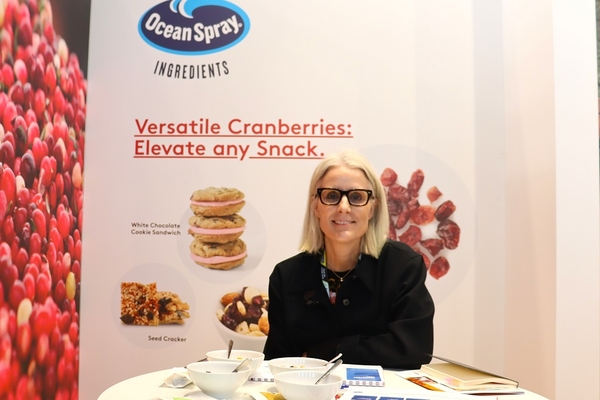 a woman with spects sitting at a trade show booth.