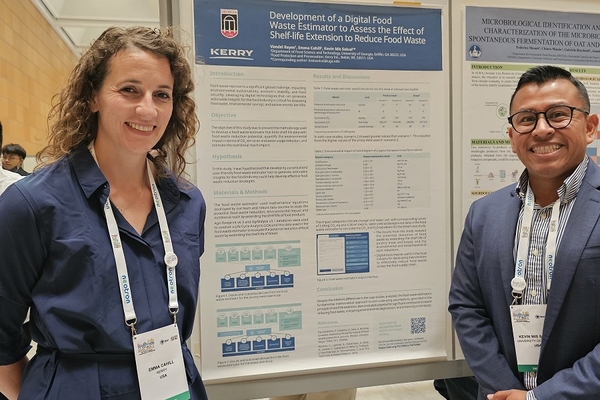 a man and woman standing with scientific poster behind them.