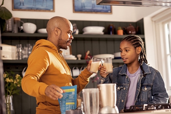 a man and his daughter holding glasses of plant based milk.